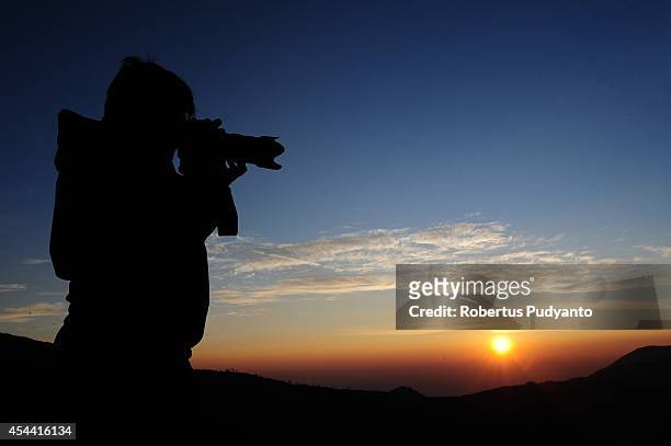 Tourist shoots sunrise at Dieng plateau during the Dieng Cultural Festival 2014 on August 31, 2014 in Dieng, Java, Indonesia. The Dieng Culture...
