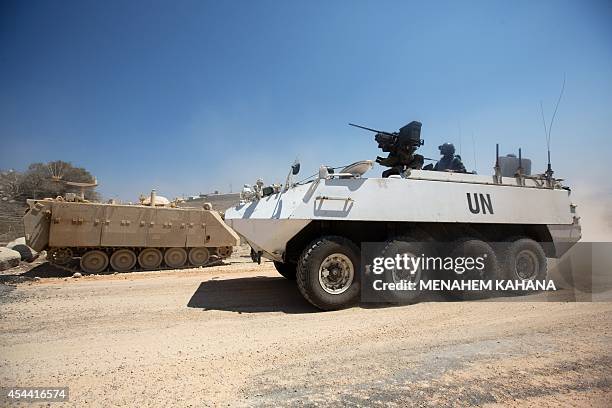 Irish members of United Nations Disengagement Observer Force convoy pass by Israeli armoured personnel carriers as they maneuver, near the border of...