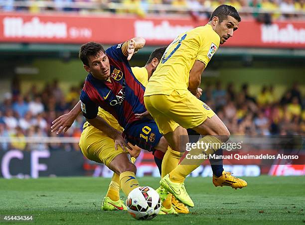 Lionel Messi of Barcelona is tackled by Cani and Mateo Pablo Musacchio during the La Liga match between Villarreal CF and FC Barcelona at El Madrigal...