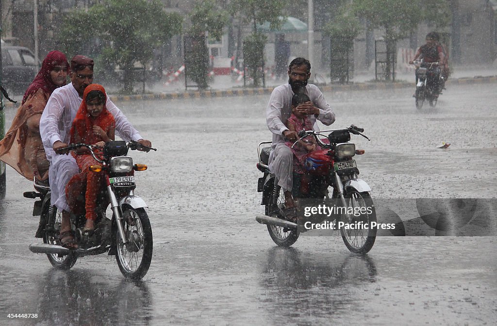 Pakistani commuters passing through the heavy monsoon rain...