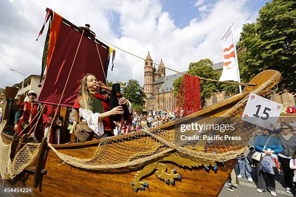 Member of the Network Lebendiges Mittelalter plays the bagpipes on a wooden boat on top of a float. The cathedral of Worms can be seen in the...