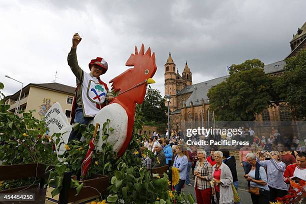 Man sits on a large wooden cock on a float in the Backfischfest parade 2014. The cathedral of Worms can be seen in the background. The first...