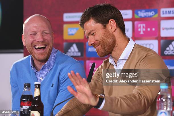 Xabi Alonso of FC Bayern Muenchen smiles with Matthias Sammer, sporting director of FC Bayern Muenchen during a press conference at Bayern Muenchen's...
