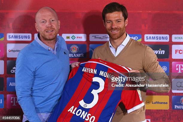 Xabi Alonso of FC Bayern Muenchen poses with Matthias Sammer, sporting director of FC Bayern Muenchen during a press conference at Bayern Muenchen's...