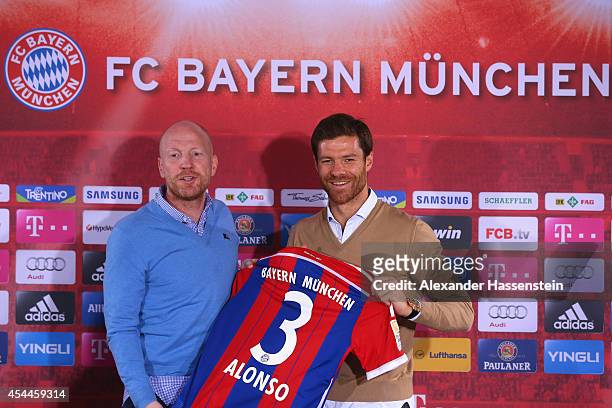 Xabi Alonso of FC Bayern Muenchen poses with Matthias Sammer, sporting director of FC Bayern Muenchen during a press conference at Bayern Muenchen's...
