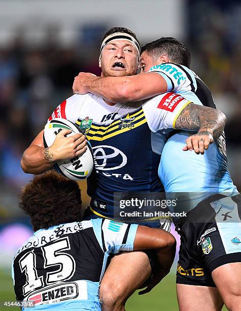 Tariq Sims of the Cowboys is tackled by Junior Roqica and Chris Heighington of the Sharks during the round 25 NRL match between the North Queensland...