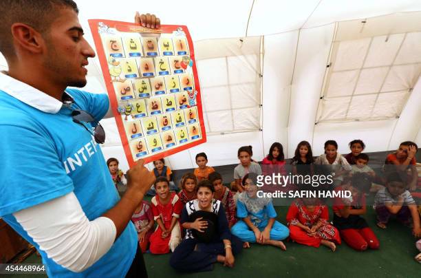 Young Iraqi's, that fled violence in the northern city of Tal Afar due to attacks by Islamic State jihadists, look up at a teacher during a class at...
