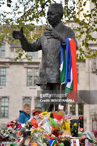 People gather around tributes and flowers laid at the base of a statue of late former South African president Nelson Mandela in Parliament Square in...
