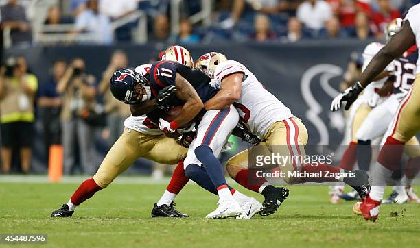 Chris Borland and Jimmie Ward of the San Francisco 49ers tackles DeVier Posey of the Houston Texans during the game at Reliant Stadium on August 28,...