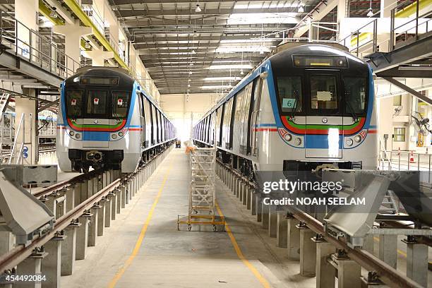 Employees of Indian Hyderabad Metro Rail check a metro train during a photo call at the Uppal Metro Rail Depot in Hyderabad on September 2, 2014. HMR...