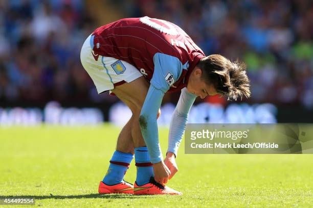 Jack Grealish of Villa ties his boot laces as his hair flows free during the Barclays Premier League match between Aston Villa and Hull City at Villa...