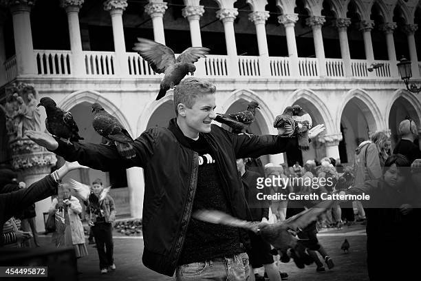 Tourist plays with pigeons in Piazza San Marco during the 71st Venice Film Festival on September 1, 2014 in Venice, Italy.