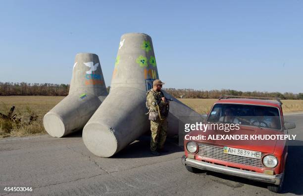Ukrainian fighter from the Azov Battalion stands guard near concrete barriers across the road on a checkpoint on the outskirts of Mariupol on...