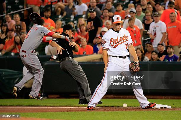 Billy Hamilton of the Cincinnati Reds runs into first base umpire Mike DiMuro after hitting an infield single as Chris Davis of the Baltimore Orioles...