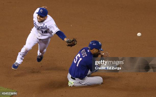 Alex Rios of the Texas Rangers slides into second for a steal as Omar Infante of the Kansas City Royals can't catch the throw from Salvador Perez in...