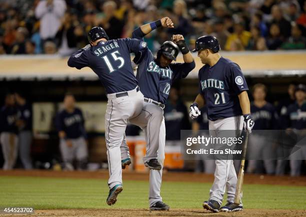 Kendrys Morales of the Seattle Mariners looks on as Robinson Cano and Kyle Seager celebrate after Seager hit a two-run home run that scored Cano in...