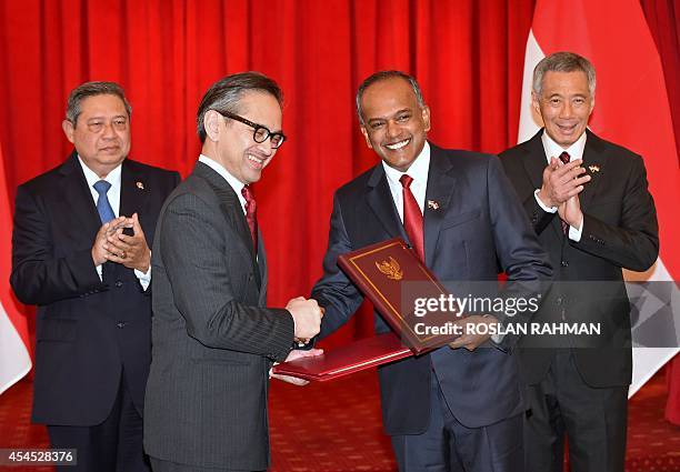 Indonesian foreign affairs minister Marty Natalegawa shakes hands with Singapore foreign affairs minister K Shanmugam as outgoing Indonesian...