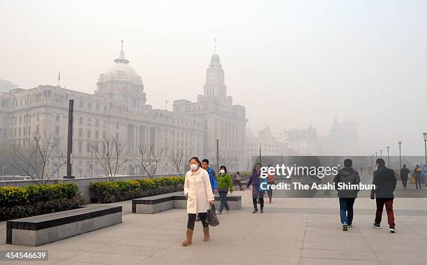 People wearing masks walks at The Bund on December 6, 2013 in Shanghai, China. Heavy smog continued to hit northern and eastern parts of China on...