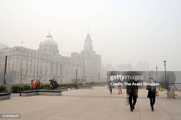 People wearing masks walks at The Bund on December 6, 2013 in Shanghai, China. Heavy smog continued to hit northern and eastern parts of China on...