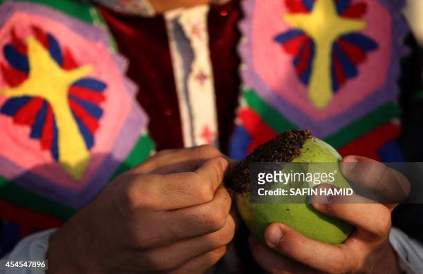 An Iraqi Kurdish girl, wearing traditional clothes decorates an apple with cloves, as a symbol of peace and love according to a Kurdish tradition on...