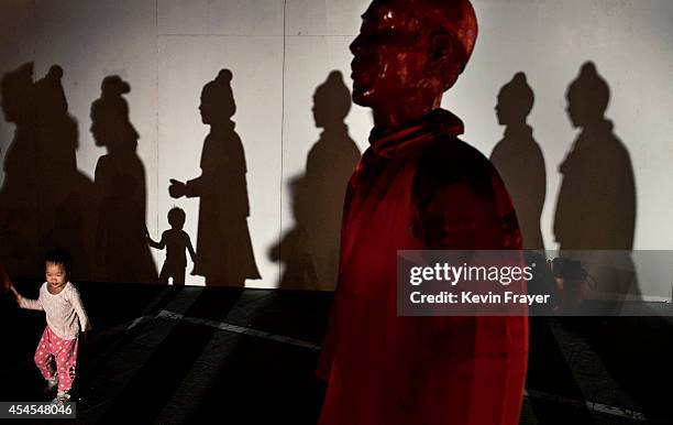 Chinese girl is walked passed a statue replicating China's famous Terracotta Warriors at an exhibtion on September 3, 2014 in Beijing, China. The...