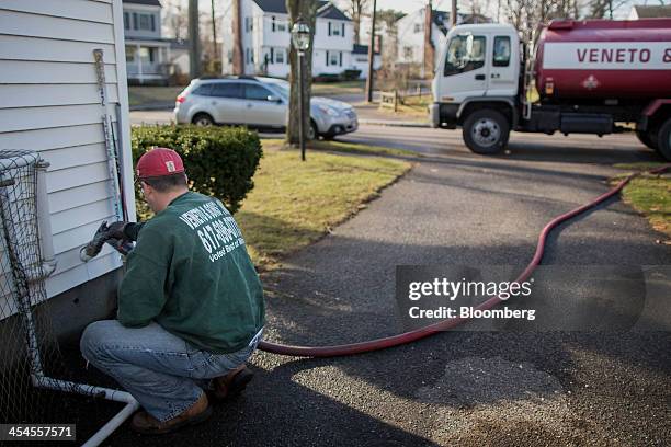 Brian Mantville, owner of Veneto & Sons Oil, pumps oil into a house while making a delivery in Milton, Massachusetts, on Saturday, Dec. 7, 2013....