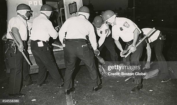 Boston Police officers wearing riot helmets and carrying batons arrest rioters in Roxbury on June 1, 1967.