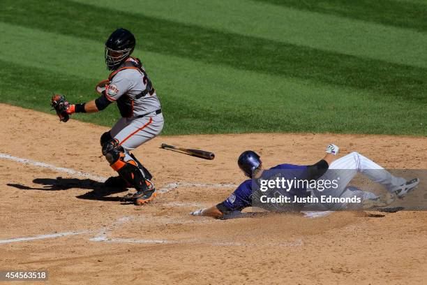 Josh Rutledge of the Colorado Rockies scores ahead of the tag attempt by catcher Buster Posey of the San Francisco Giants during the sixth inning at...