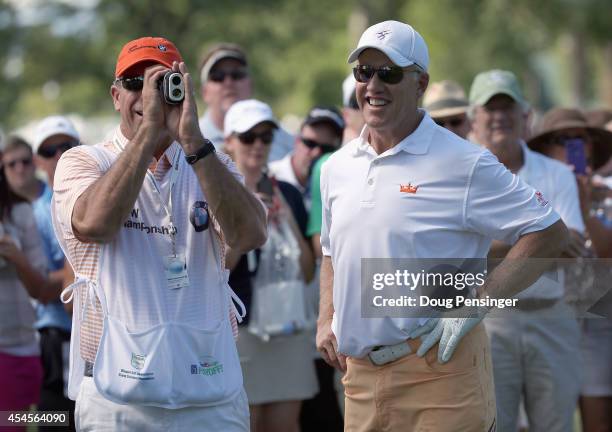 John Elway observes as his caddie George Solich measures the distance to the green as Elway prepares to take his second shot on the second hole...