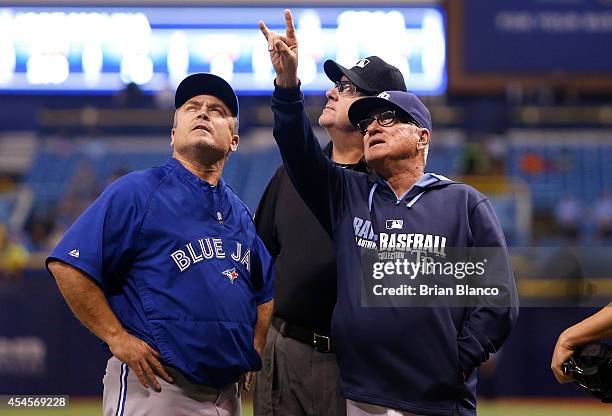 Managers John Gibbons of the Toronto Blue Jays and Joe Maddon of the Tampa Bay Rays speak with umpire Gary Cederstrom as they call a weather-related...