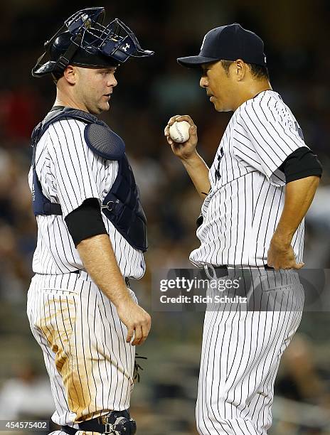 Catcher Brian McCann talks with Hiroki Kuroda of the New York Yankees walks off the mound in the seventh inning against the Boston Red Sox in a MLB...