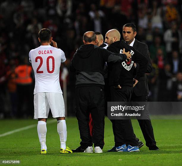 Pitch invader is escorted off the field by Turkey's head coach Fatih Terim during an international friendly match between Denmark and Turkey at...