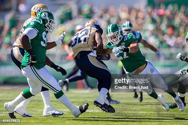Brian Peters of the Saskatchewan Roughriders dives to make a tackle on Nic Grigsby of the Winnipeg Blue Bombers in a game between the Winnipeg Blue...