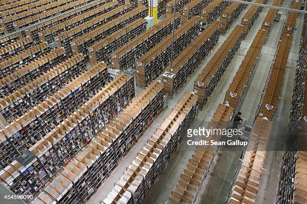Worker pushes a cart among shelves lined with goods at an Amazon warehouse on September 4, 2014 in Brieselang, Germany. Germany is online retailer...