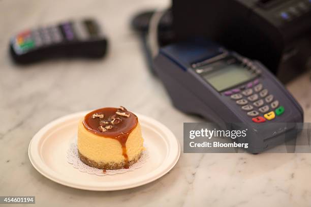 Mini cake sits on a paper plate beside a card payment machine at the cash desk inside the new Magnolia Bakery cake store in Moscow, Russia, on...