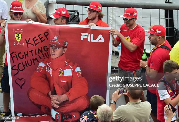 Man takes a photograph of Scuderia Ferrari's supporters as they hold a banner that reads, "Keep fighting Schumi " referring to former F1 legend...