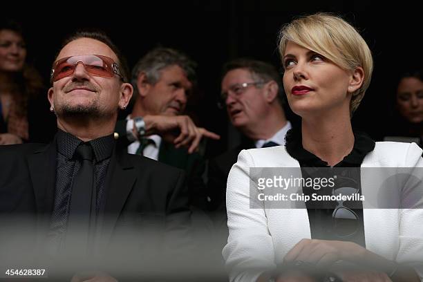 Singer Bono and South African actor Charlize Theron arrive for the official memorial service for former South African President Nelson Mandela at FNB...
