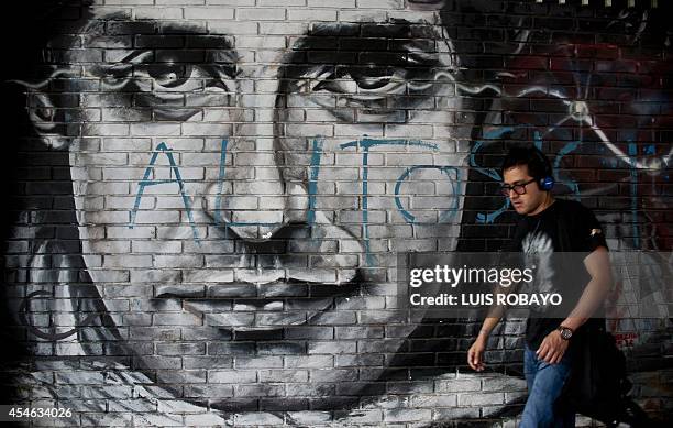 Man walks by a graffiti depicting Argentine musician Gustavo Cerati, in Cali, Colombia, on September 4, 2014. Cerati, one of the greatest stars of...
