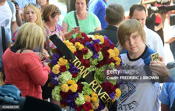 Justin Buckner, visiting from West Virginia, snaps a selfie beside a wreath of flowers placed on the Hollywood Walk of Fame Star for Joan Rivers in...