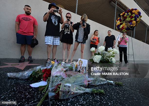 People stand beside flowers that were placed on the Hollywood Walk of Fame Star for Joan Rivers in Hollywood, California on September 4 following...