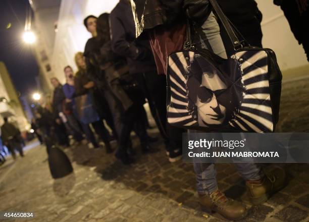 Woman holds a bag with a portrait of late Argentine musician Gustavo Cerati while lining up during his funeral near the legislative building in...