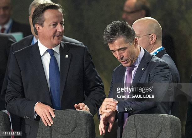 Nato Secretary General Anders Fogh Rasmussen checks his watch alongside British Prime Minister David Cameron during a meeting on the second day of...
