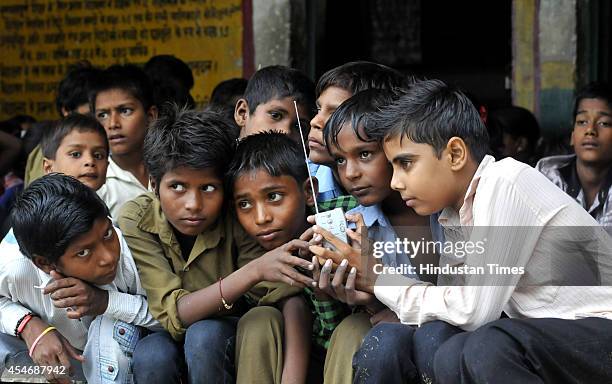 Indian school children crowd around a radio as they listen to a broadcast by Indian Prime Minister Narendra Modi delivering his Teachers' Day speech...