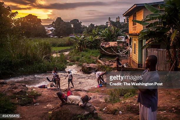 Residents of the town of Kailahun gather along a river at dusk on Tuesday, August 19, 2014.