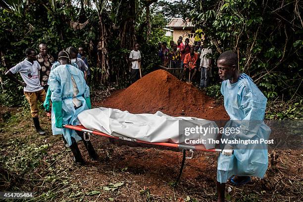 Members of a Red Cross burial team prepare to bury the body of a woman suspected of dying of Ebola in the village of Dia, Sierra Leone, on Monday,...