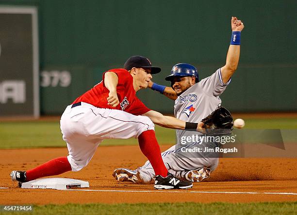 Melky Cabrera of the Toronto Blue Jays moves to third base as Brock Holt of the Boston Red Sox takes a late throw in the first inning against Boston...