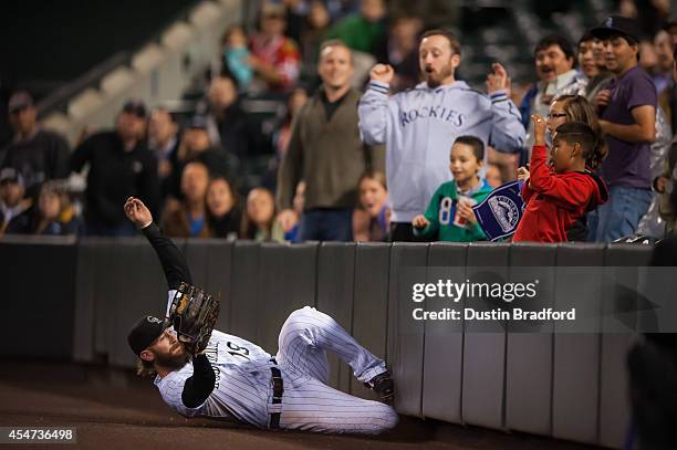 Charlie Blackmon of the Colorado Rockies makes a sliding catch in foul territory for an eighth inning out against the San Diego Padres at Coors Field...