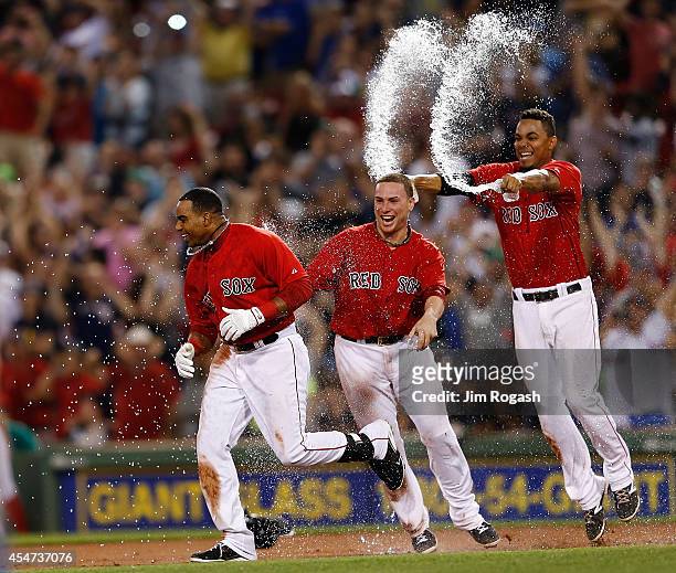 Yoenis Cespedes of the Boston Red Sox celebrates with teammates Christian Vazquez and Xander Bogaerts of the Boston Red Sox after knocking in the...