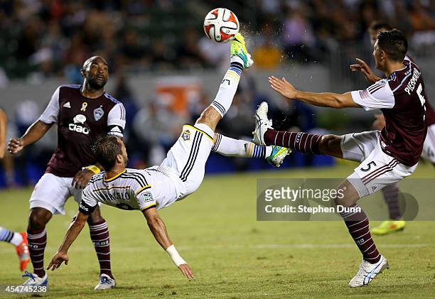 Marcelo Sarvas of the Los Angeles Galaxy gets off a shot with a bicycle kick between Marvell Wynne and Thomas Piermayr of the Colorado Rapids at...