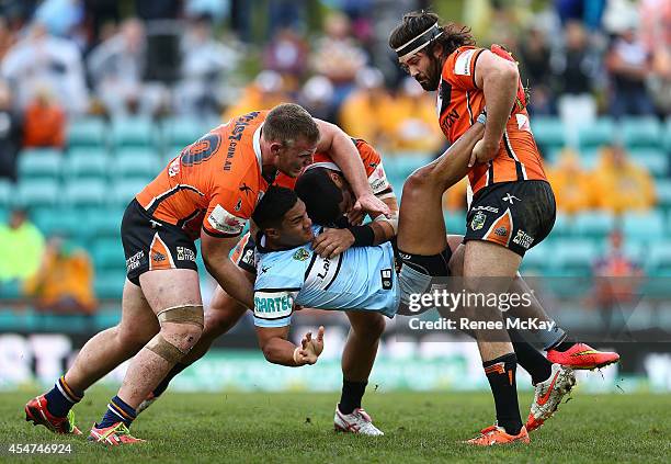 Ricky Leutele of the Sharks is tackled by Matt Lodge and Aaron Woods of the Tigers during the round 26 NRL match between the Wests Tigers and the...